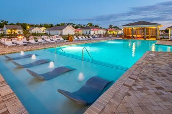 night view of pavilion pool and in-pool lounge chairs with sundeck